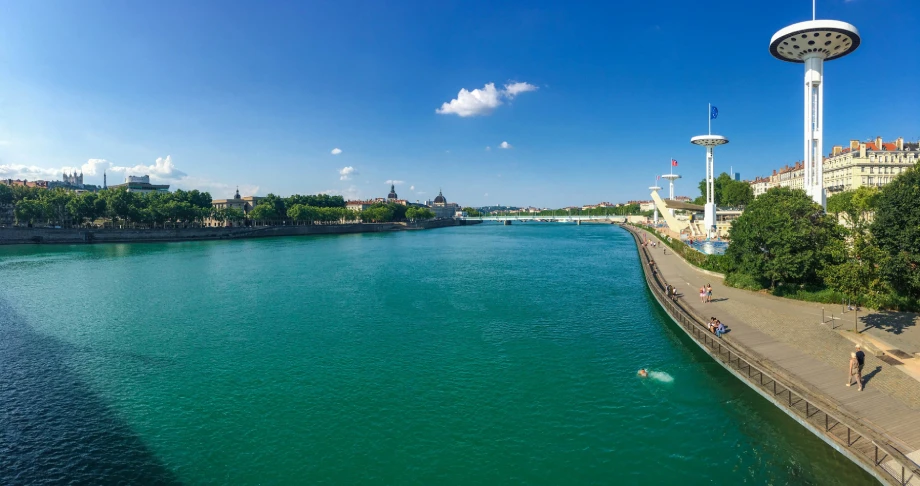 Vue aérienne des berges du Rhône à Lyon par beau temps, avec la piscine en plein air et ses plongeoirs emblématiques