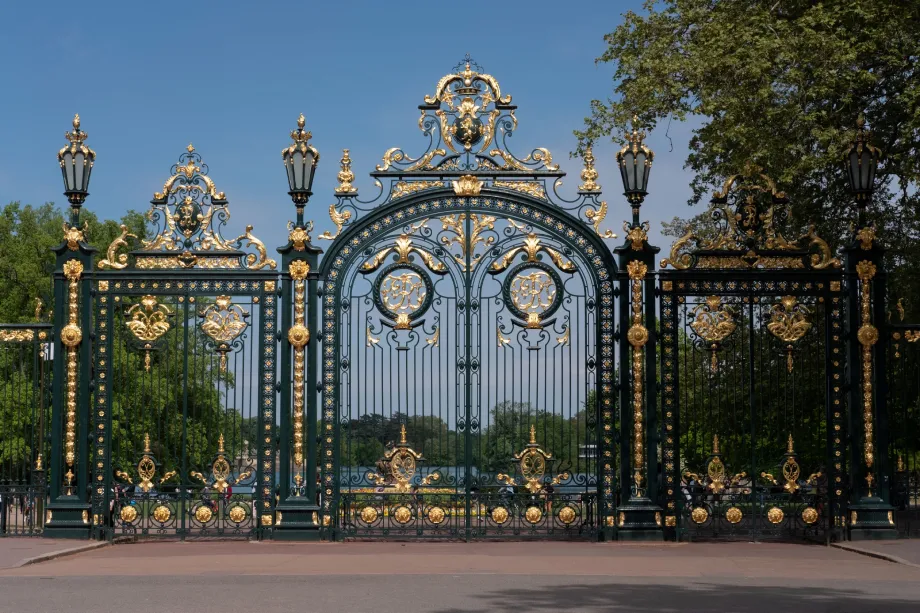 Grilles monumentales en fer forgé doré à l'entrée du parc de la Tête d'Or à Lyon, sous un ciel bleu ensoleillé