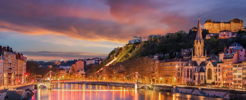Quais de Saone a Lyon au crepuscule avec eglise, immeubles illumines et reflets sur l’eau