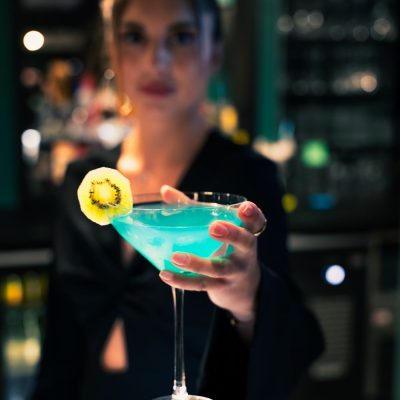 Cliente dégustant un cocktail bleu au bar de l’Hôtel Villa Berlioz Lyon