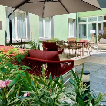Terrasse extérieure de l’Hôtel Villa Berlioz à Lyon, avec mobilier confortable, parasol et végétation.
