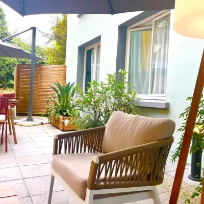 Fauteuils et table sous parasol sur la terrasse jardin de l’Hôtel Villa Berlioz Lyon