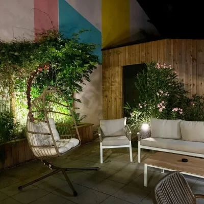 Salon de jardin éclairé de nuit avec fauteuil suspendu sur la terrasse de l’Hôtel Villa Berlioz Lyon
