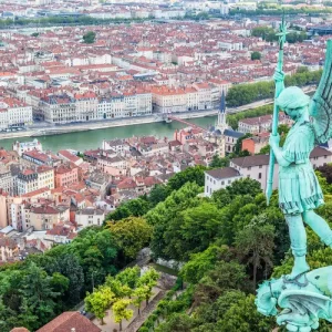 Vue panoramique de Lyon depuis Fourvière avec la statue de l’Archange Saint-Michel au premier plan.