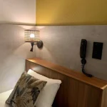 Headboard and wall lighting detail in a small single room at Villa Berlioz Hotel Lyon